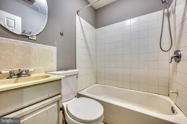 a bathroom with a granite countertop bathtub sink vanity mirror and toilet