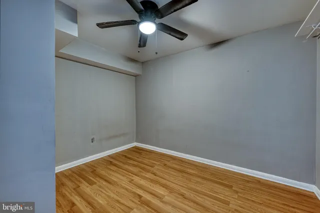 an empty room with a ceiling fan and wooden floor