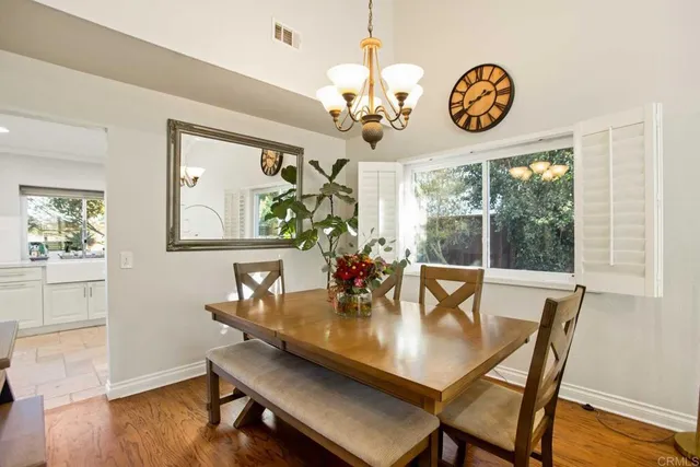 a dining room with wooden floor a chandelier a wooden table and chairs