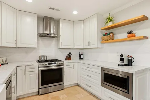 a kitchen with stainless steel appliances granite countertop a stove a sink and a microwave