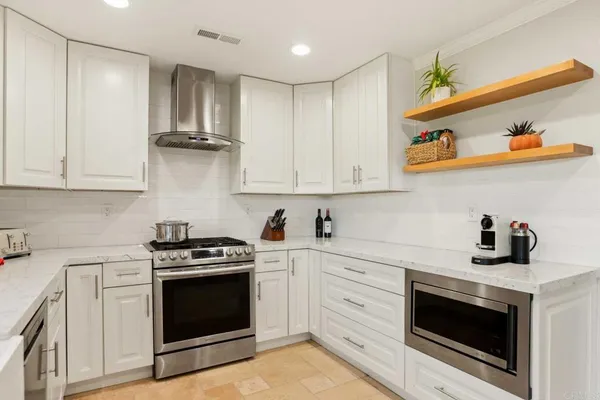 a kitchen with stainless steel appliances granite countertop a stove a sink and a microwave