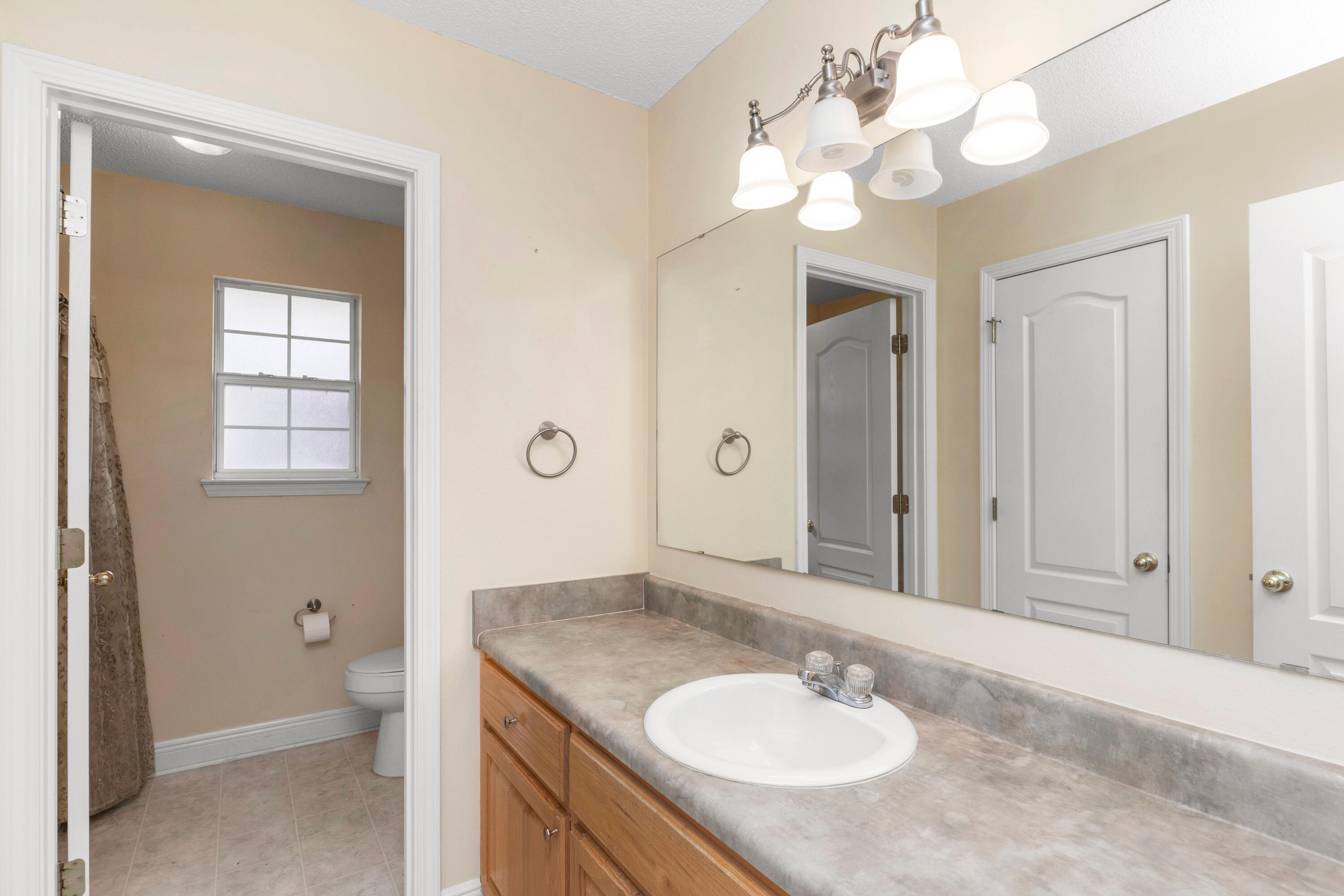 238 Foxchase Way Crestview, FL 32536 - Photo 14 of 33 a bathroom with a granite countertop sink a toilet and a mirror
