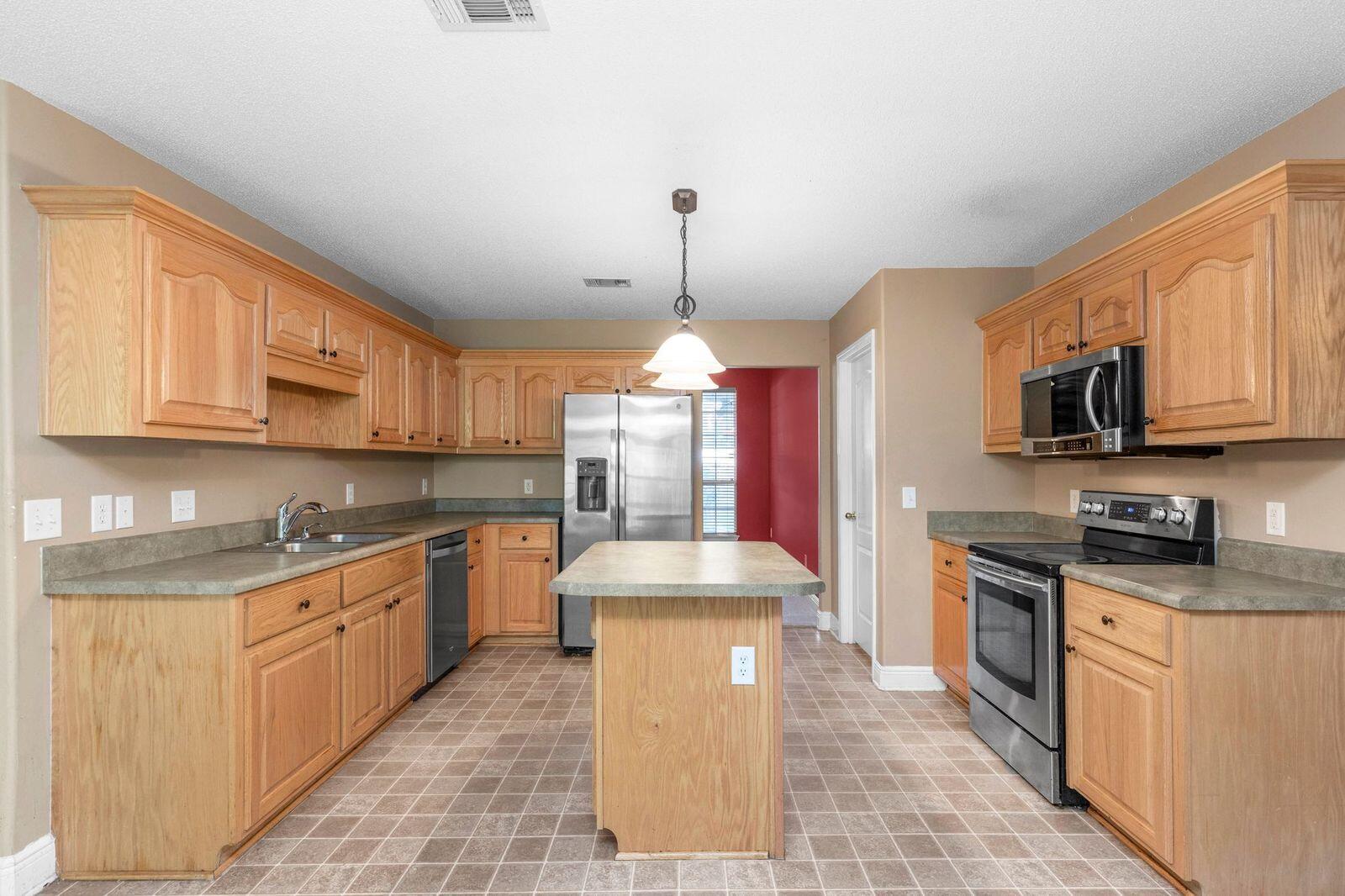 238 Foxchase Way Crestview, FL 32536 - Photo 9 of 33 a large kitchen with stainless steel appliances granite countertop a stove a sink dishwasher and a microwave oven with white cabinets