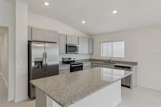 a kitchen with kitchen island granite countertop a sink stove and refrigerator