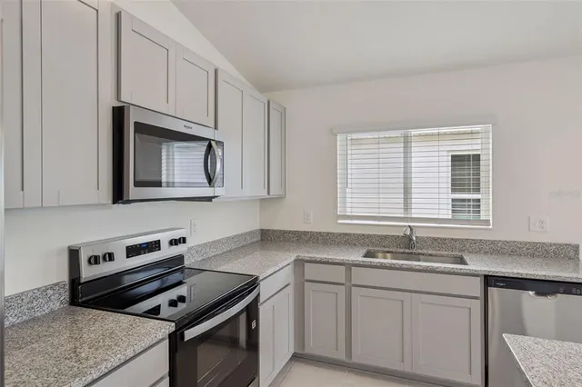 a kitchen with granite countertop cabinets stainless steel appliances a sink and a window