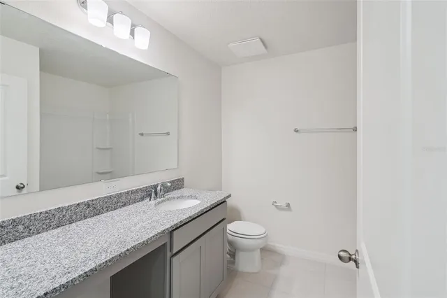 a bathroom with a granite countertop sink a toilet and a mirror