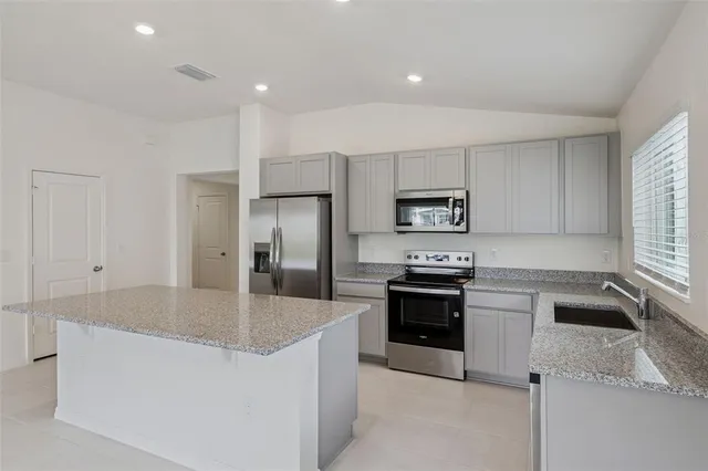a kitchen with stainless steel appliances granite countertop a sink a stove and refrigerator
