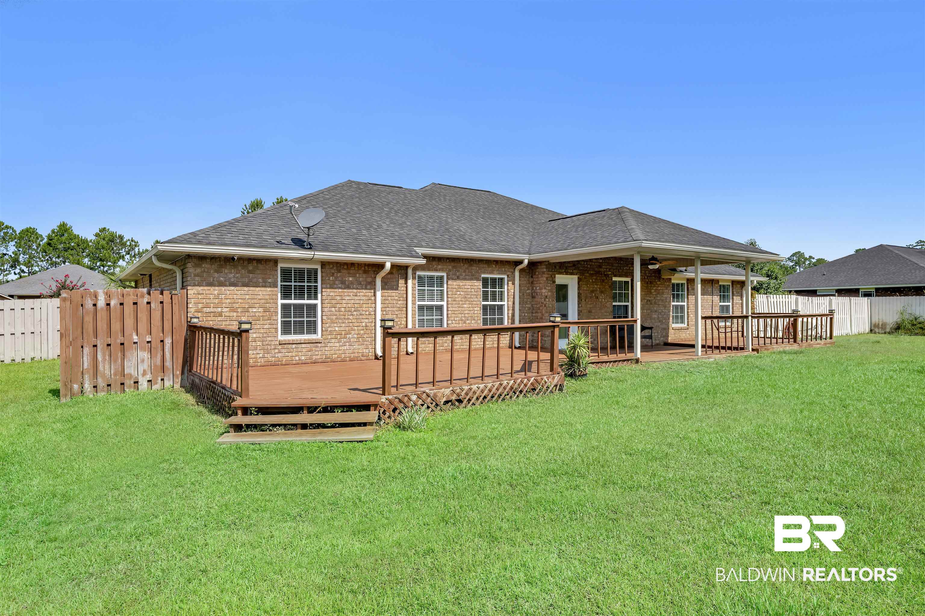10147 Lyttleton Loop Lillian, AL 36549 - Photo 5 of 29 Expansive green lawn bordering a brick exterior with a multi-level wood deck