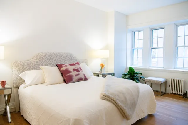 a bedroom with a bed a mirror and a window