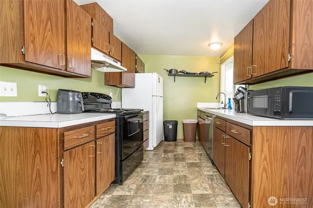 a kitchen with stainless steel appliances granite countertop a stove a sink dishwasher and a refrigerator with wooden cabinets