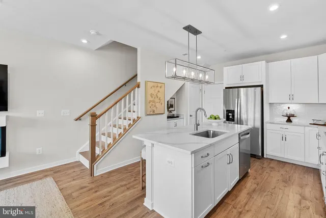 a kitchen with sink a refrigerator and wooden floor