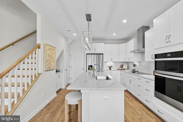 a kitchen with granite countertop a sink a stove refrigerator and cabinets