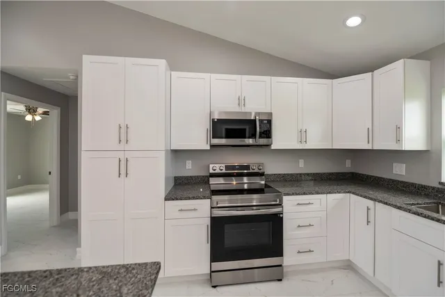 a kitchen with granite countertop white cabinets and stainless steel appliances