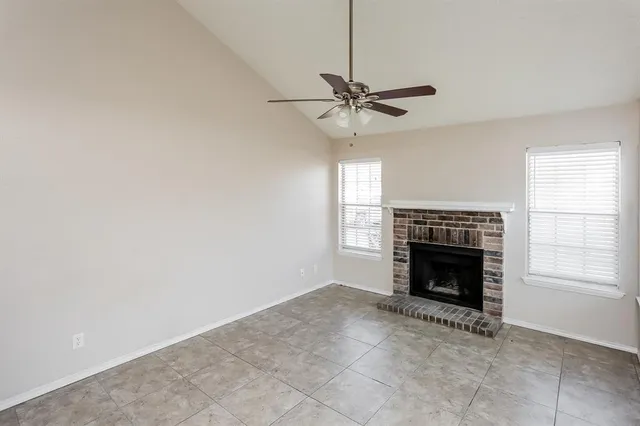 a view of an empty room with chandelier fan and fire place