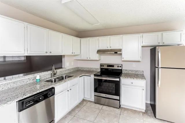a kitchen with granite countertop white cabinets and white appliances