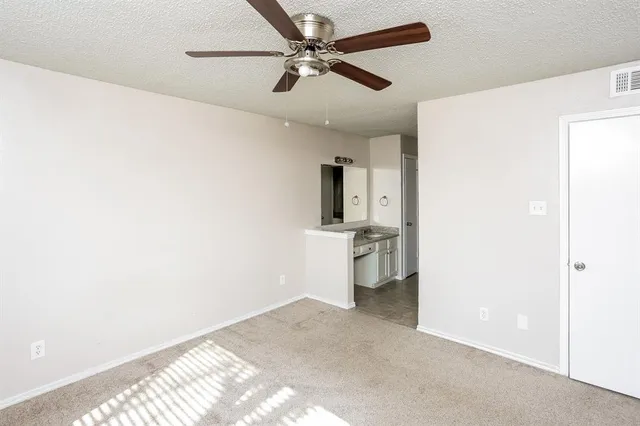 a view of a room with a ceiling fan and a refrigerator