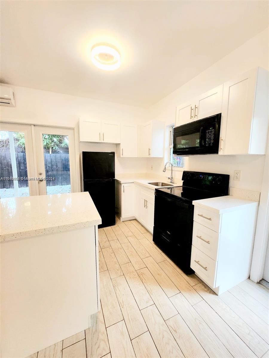 261 Northwest 50th Street, Unit R Miami, FL 33127 - Photo 4 of 10 a living room with a couch and a flat screen tv