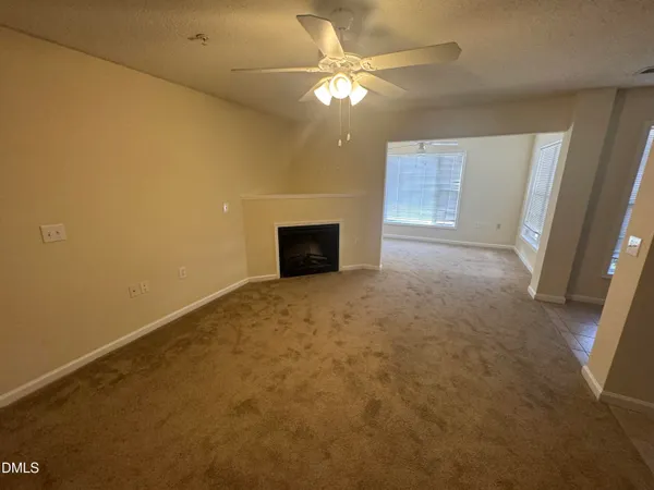 an empty room with a fireplace and a chandelier fan