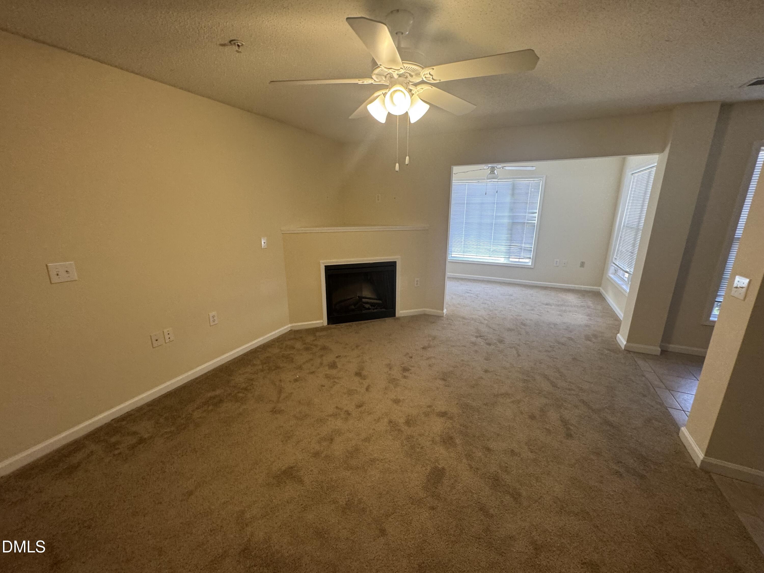 2511 Huntscroft Lane, Unit 101 Raleigh, NC 27617 - Photo 6 of 11 an empty room with a fireplace and a chandelier fan