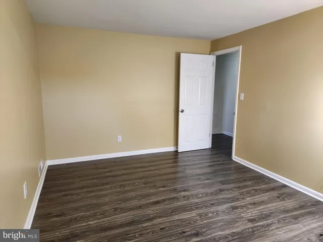 a view of an empty room with wooden floor and closet