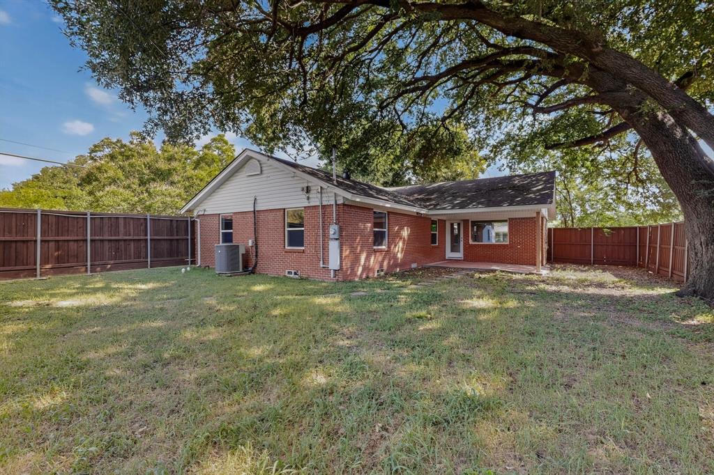 405 Easton Road Dallas, TX 75218 - Photo 30 of 36 Expansive backyard featuring a red brick exterior, a mature tree providing shade, a wood privacy fence, and a concrete patio