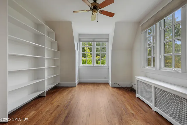 a view of an empty room with a window and wooden floor