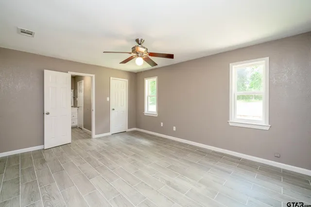 a view of empty room with wooden floor and fan