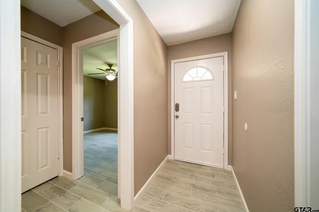 an empty room with wooden floor fan and windows