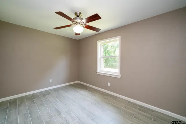an empty room with wooden floor fan and windows