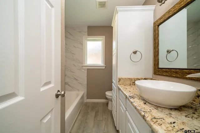 a bathroom with a granite countertop sink and a toilet