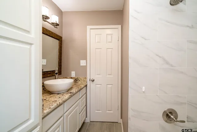 a bathroom with a granite countertop sink and a mirror