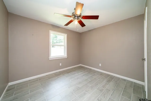 an empty room with wooden floor and a ceiling fan