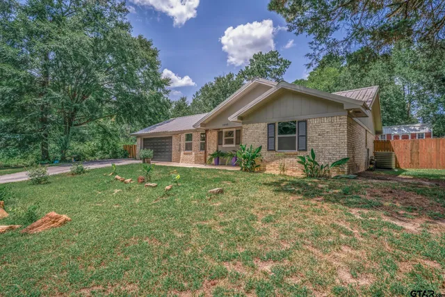 a view of a house with a yard and a large tree