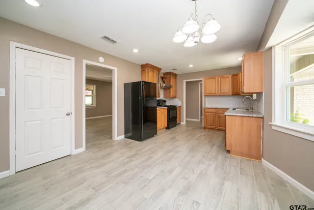 a kitchen with granite countertop a refrigerator stove top oven and sink