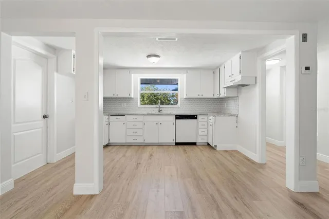 a kitchen with white cabinets and wooden floor