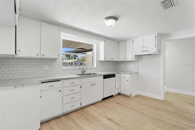 a kitchen with granite countertop white cabinets and white appliances