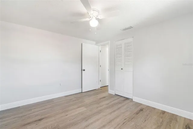 an empty room with wooden floor and a ceiling fan