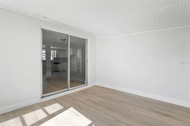 an empty room with wooden floor and a bathroom view
