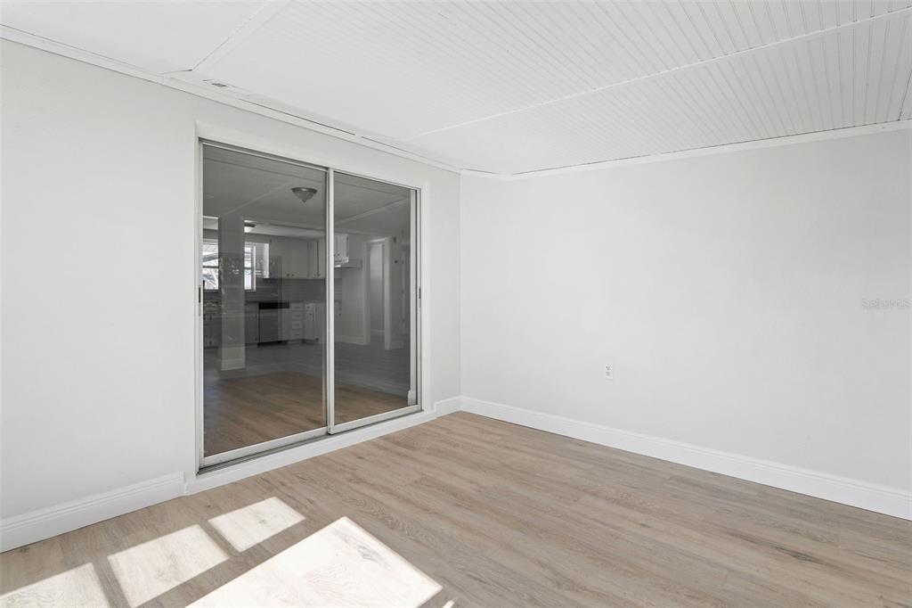 10536 Laburnum Drive Port Richey, FL 34668 - Photo 23 of 33 an empty room with wooden floor and a bathroom view