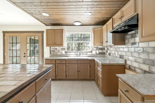 a kitchen with granite countertop a sink window and cabinets