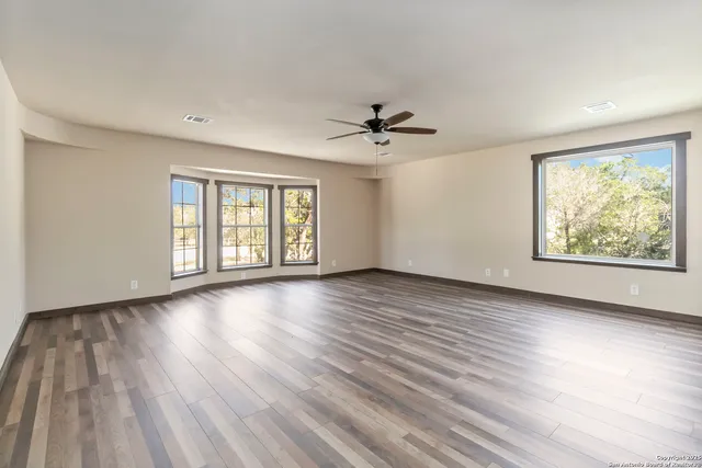 an empty room with wooden floor and windows