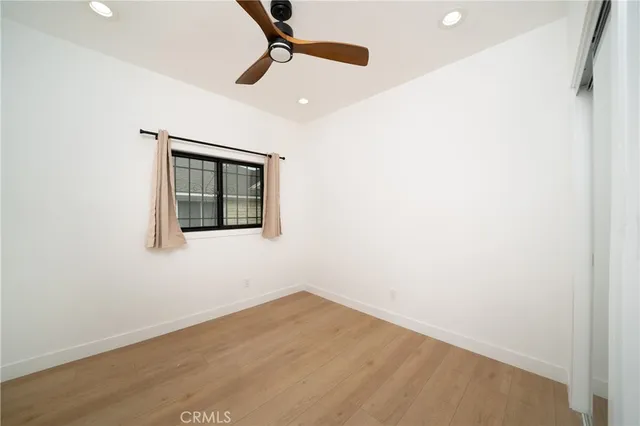 a view of a small space with wooden floor a ceiling fan and window