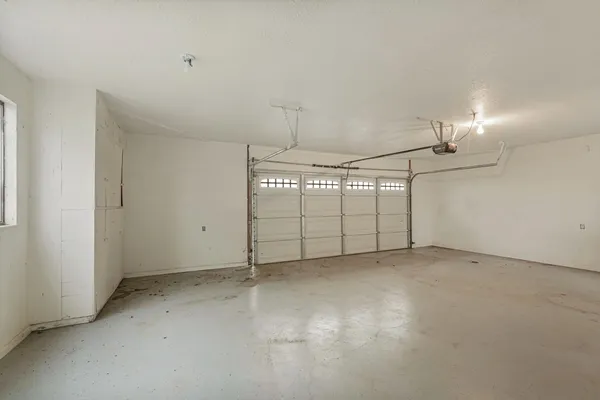 an empty room with chandelier fan and windows