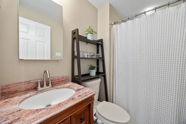 a bathroom with a granite countertop sink toilet and shower