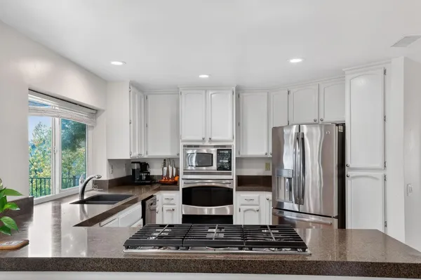 a living room with stainless steel appliances granite countertop a refrigerator and a stove top oven
