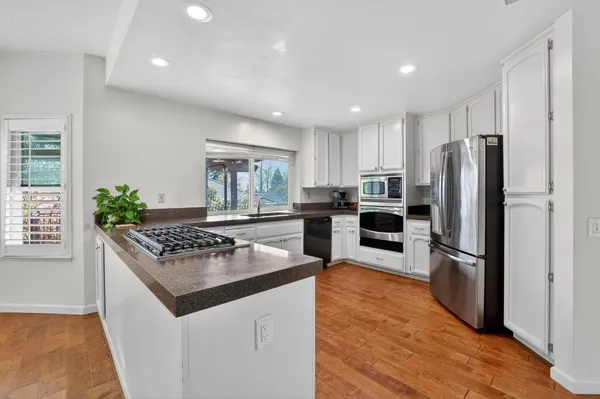 a kitchen with granite countertop a refrigerator and a stove top oven