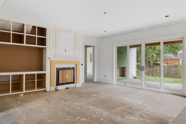 a view of an empty room with a fireplace and large windows