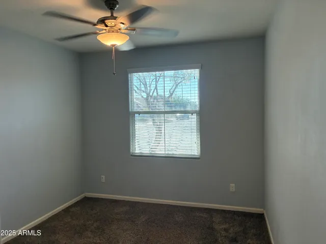 an empty room with a window and a fan