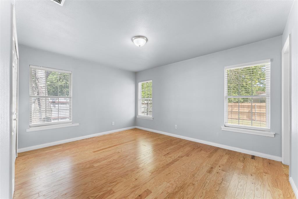 612 East 8th Street Kemp, TX 75143 - Photo 16 of 25 Light wood-finish flooring with light gray walls, two windows featuring white blinds, and a flush mount ceiling light fixture