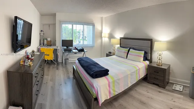 a bedroom with a bed and a flat tv screen on dresser